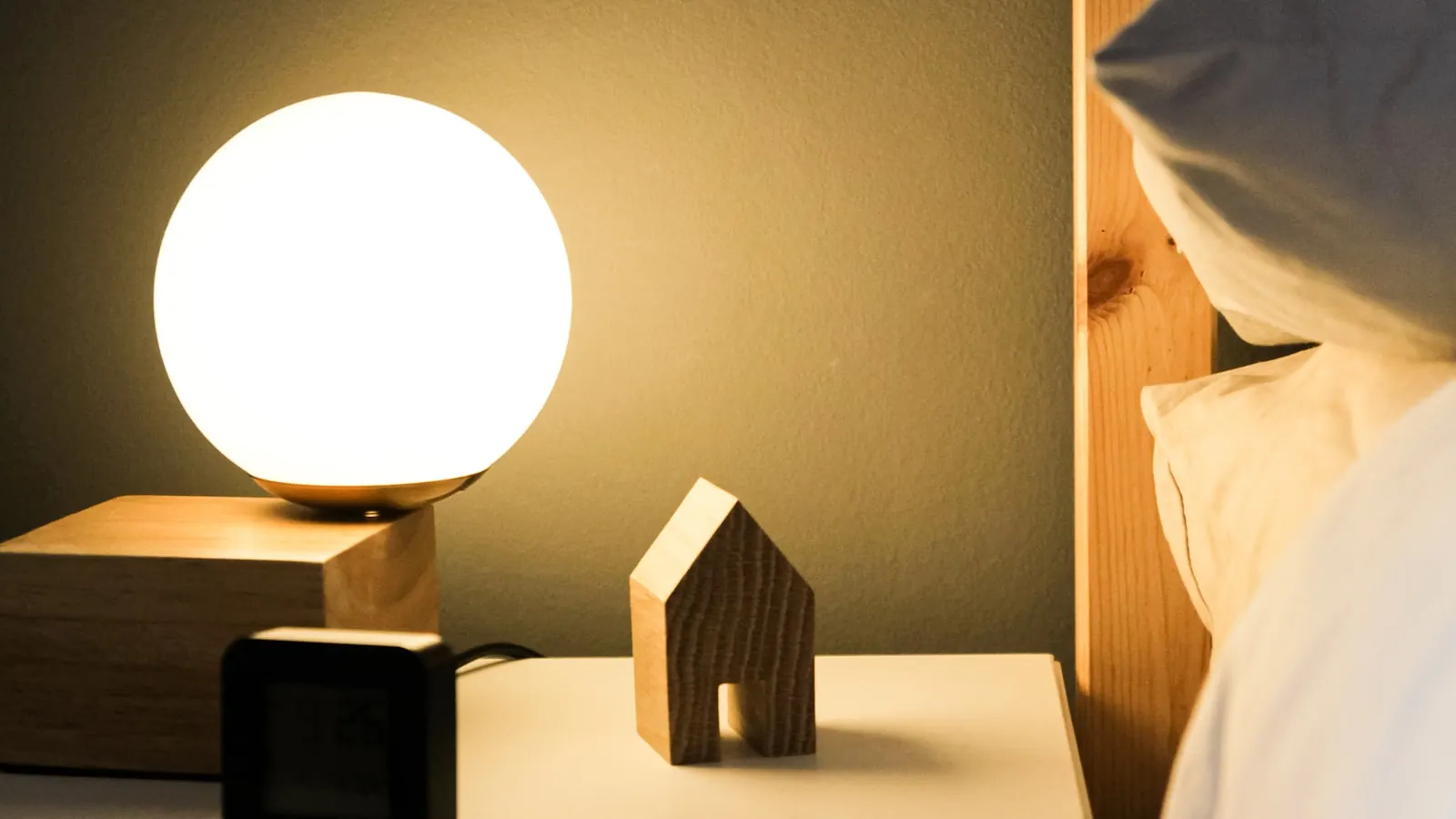 A digital clock glowing on a nightstand in a dim bedroom.