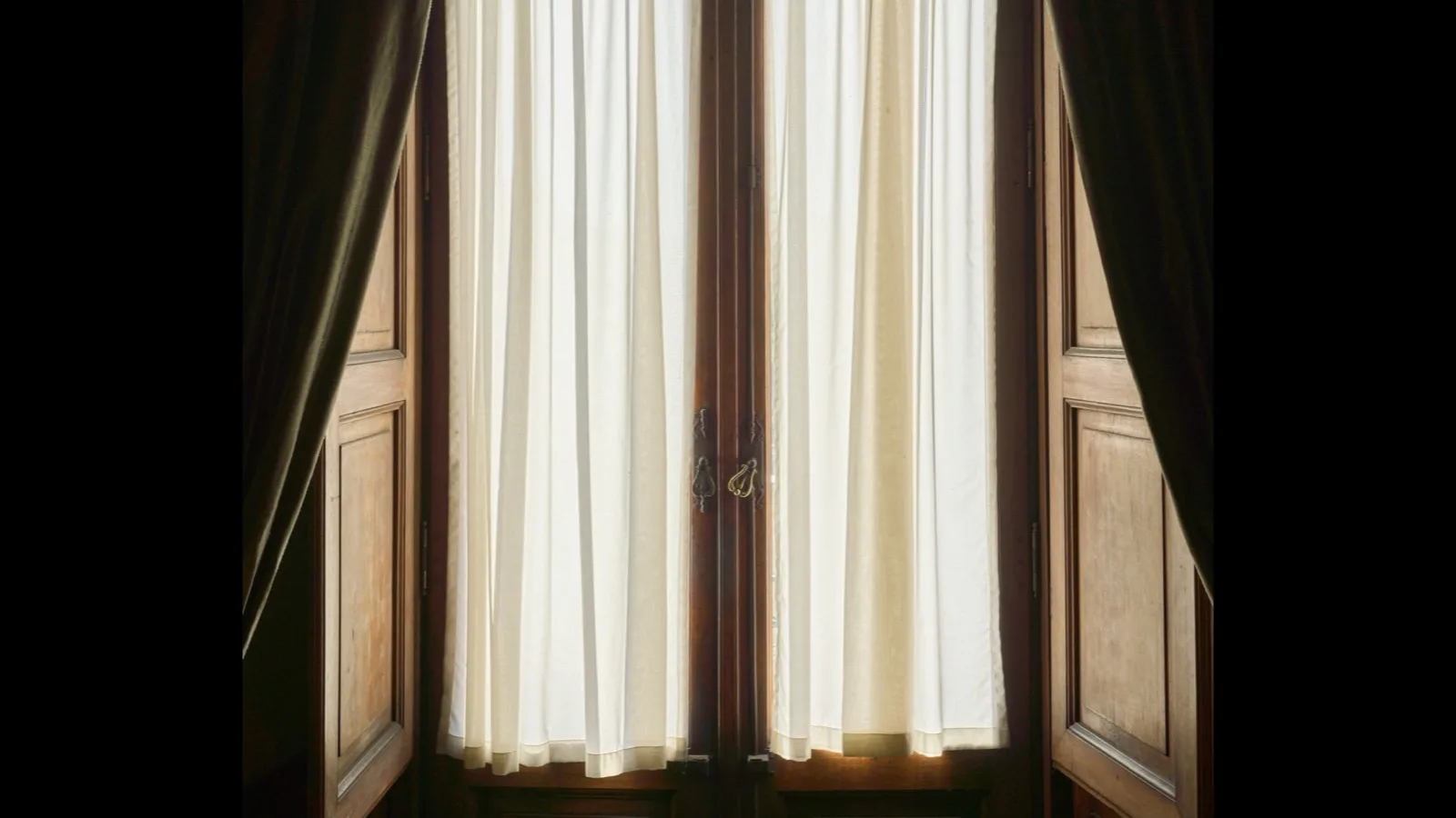 A window with light curtains, suggesting a cool room at night.