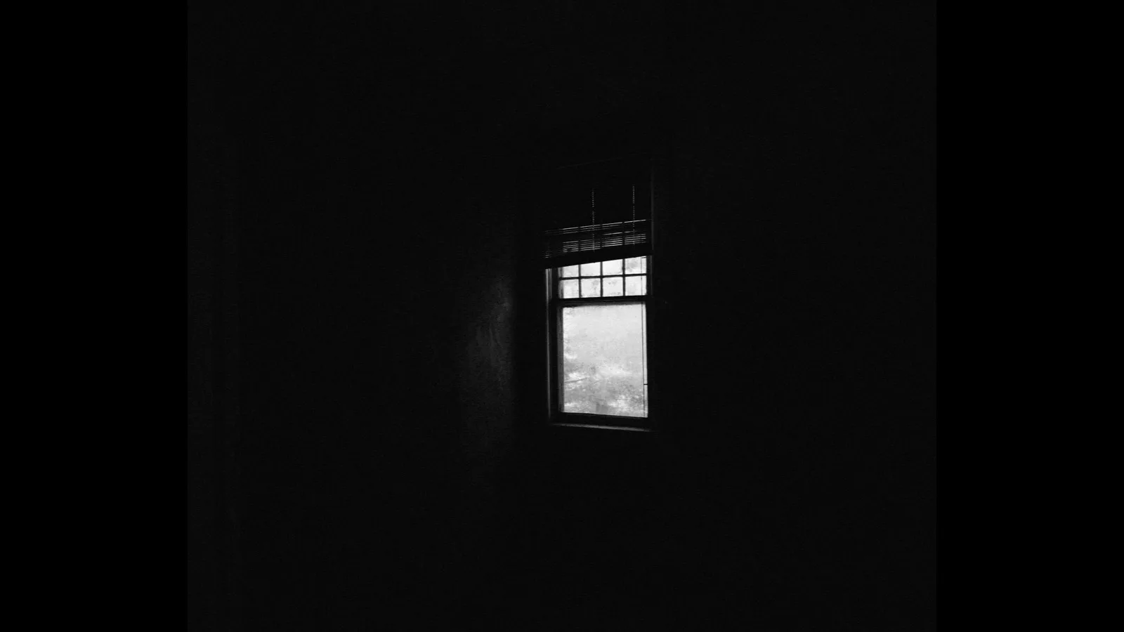 A dark window looking out at the night sky from inside a quiet room.