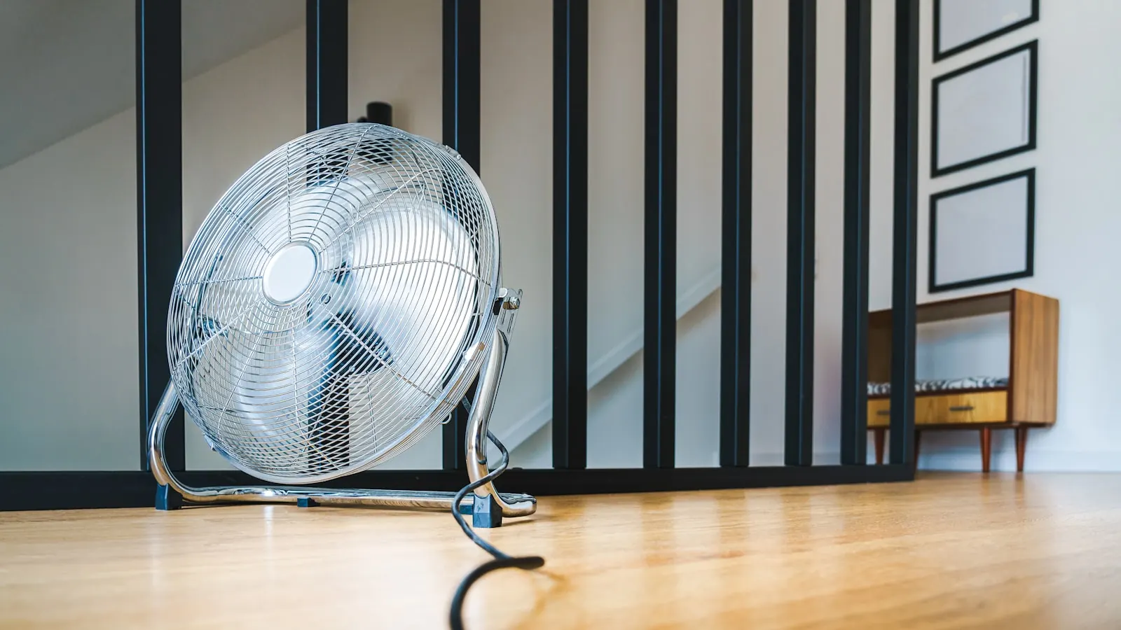 An electric fan on the floor of a warm bedroom at night.