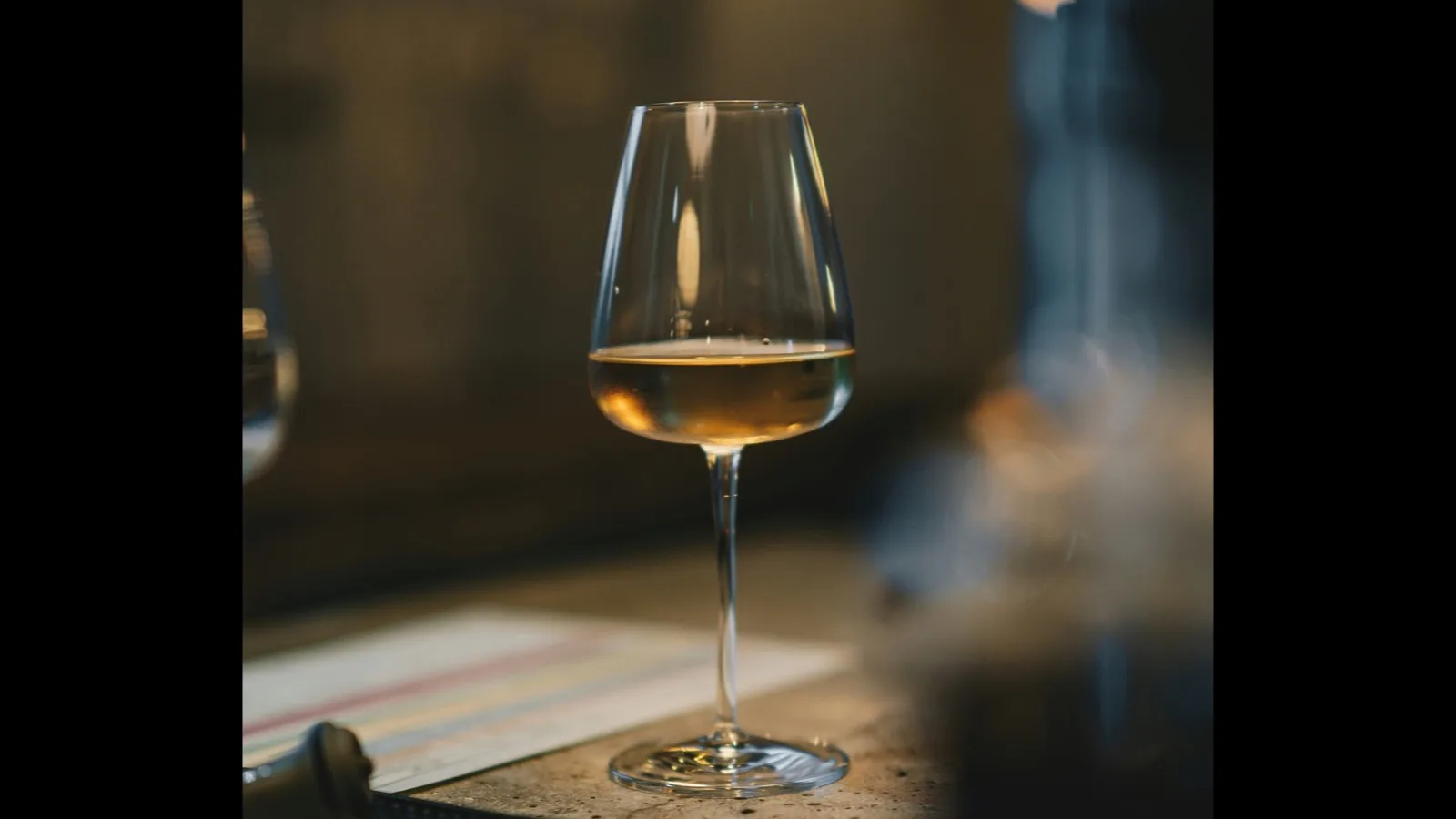 A single glass of wine on a table in the evening.